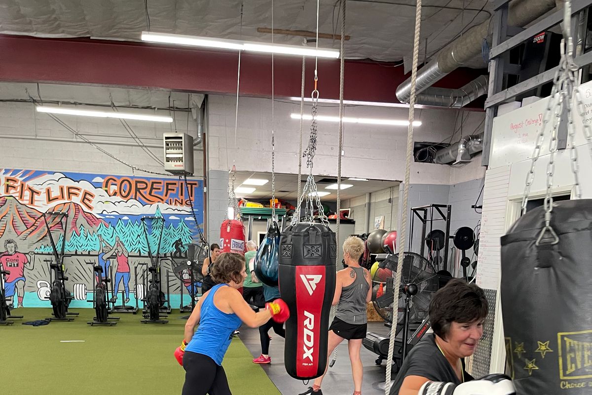 A view of CoreFit during a COMPASS class with members hitting a line of punching bags.