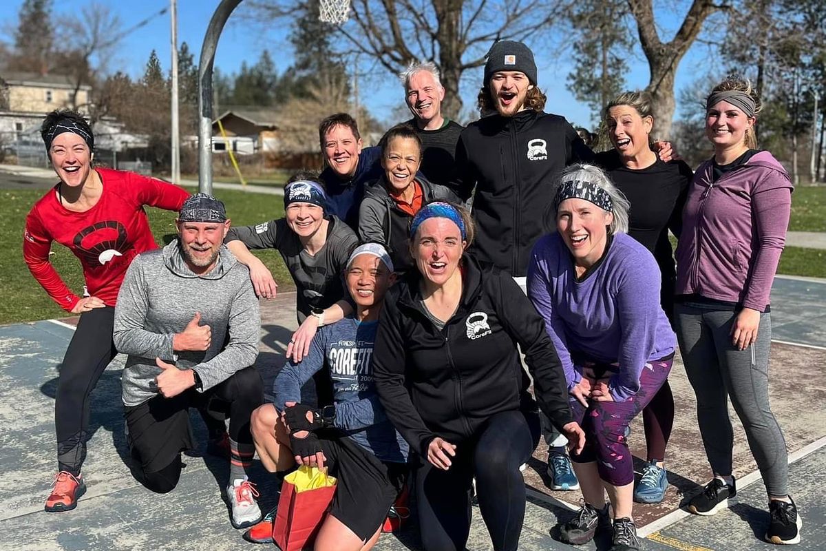 A group of 12 CoreFit members pose for an outdoor photo with smiles on their faces.