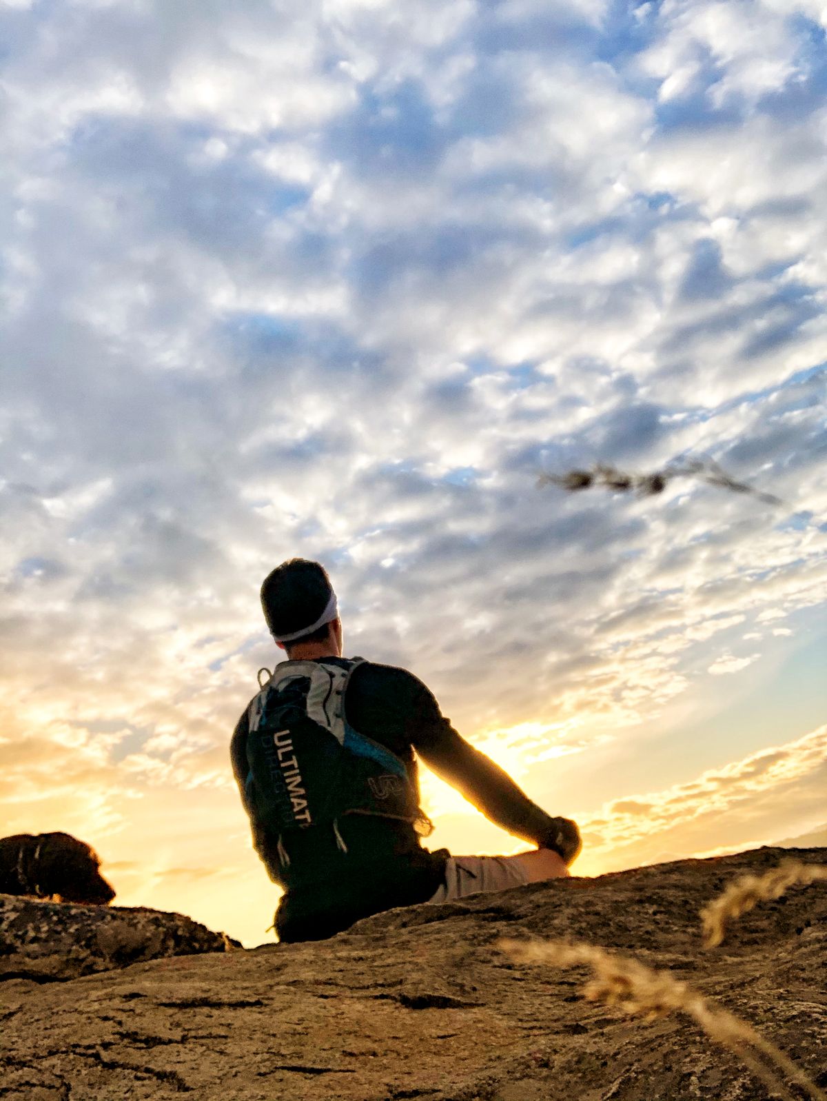 Owner Kurt sits in a meditative stance atop a rock at sunset, facing the horizon.