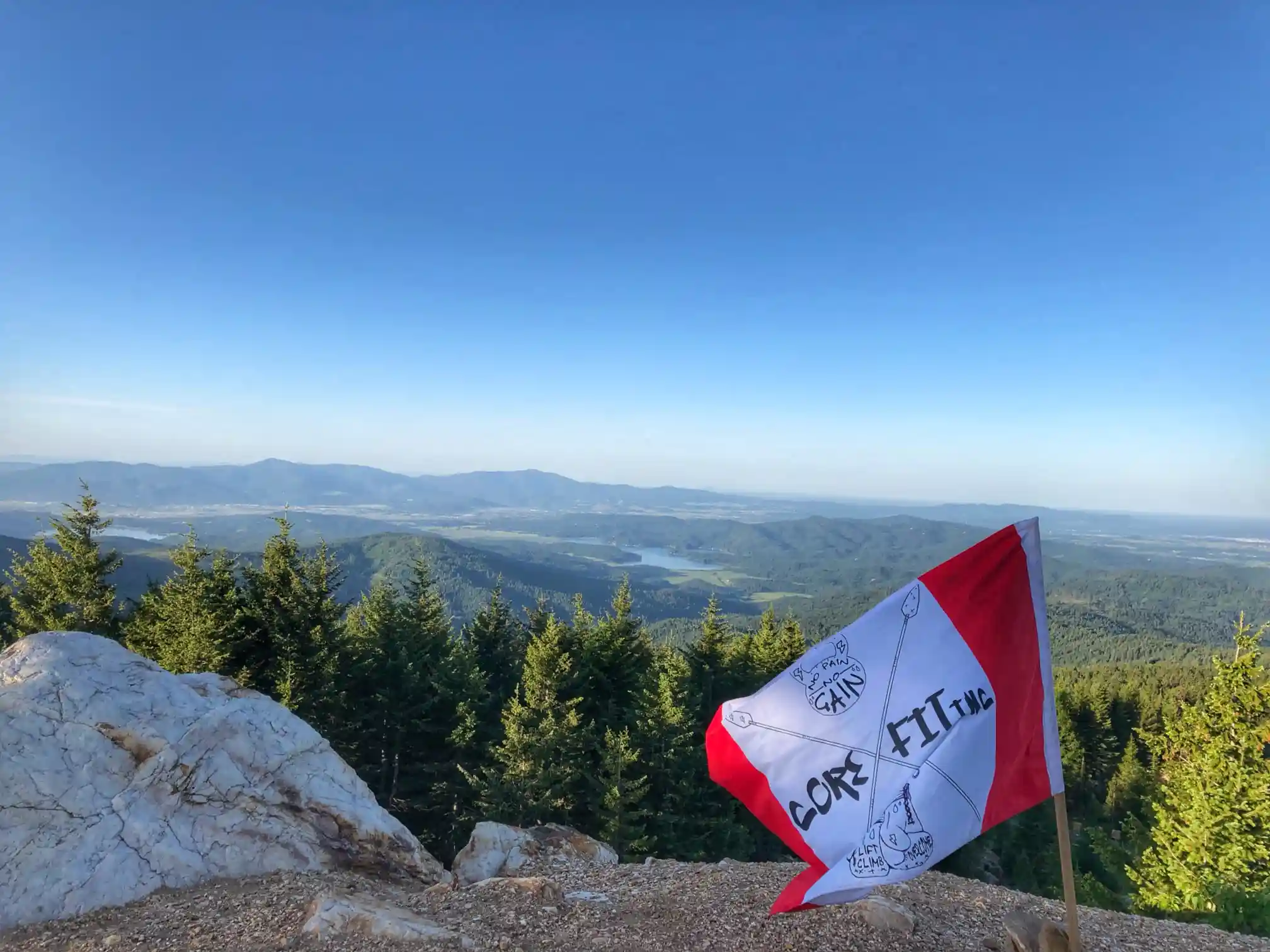 backdrop image; a view from a mountain top with a CoreFit flag planted slightly right of center