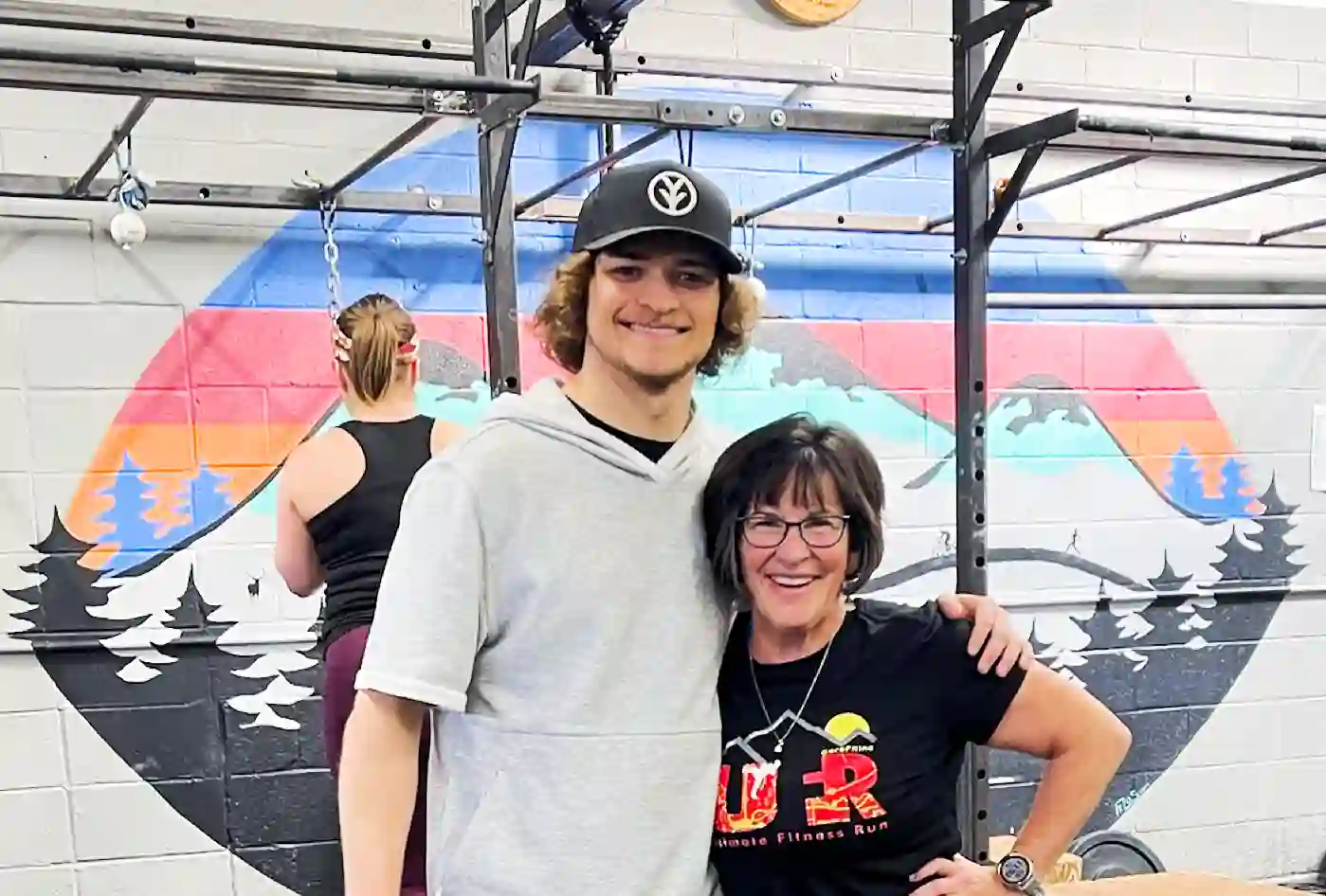 Ellis stands with his arm around CoreFit member Cindi, both smiling, inside of CoreFit.